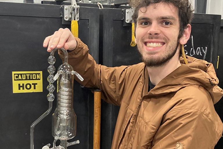 Student holding a finished piece of scientific glass apparatus