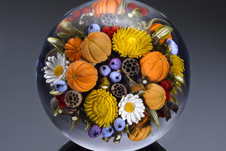 Glass paperweight by artist David Graeber with flowers, berries, and pumpkins