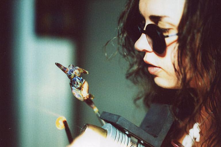 Artist Angela McHale sculpting a female figure at the torch