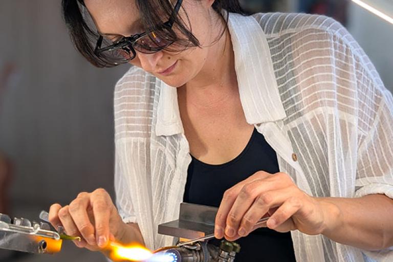 Artist Oksana Puzhalova working glass with a torch