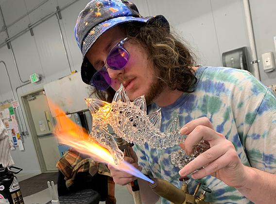 Student working on a torch to create a glass seahorse sculpture