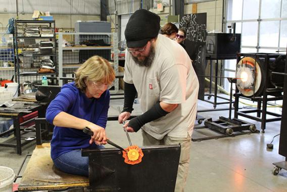 Man teaching a woman glassblowing 