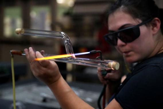 Student making scientific glass using a hand held torch