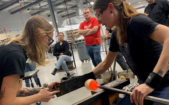 Two woman working in a glassblowing studio